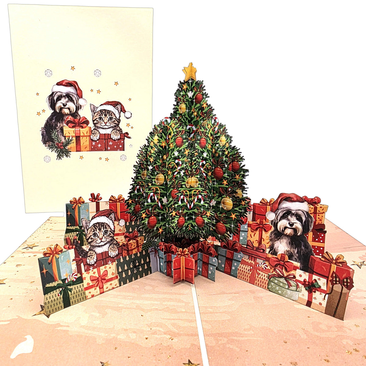A 3D pop-up cardboard Christmas greeting card featuring a decorated Christmas tree, wrapped presents, and two dogs wearing Santa hats, shown with the flat front design card behind it.