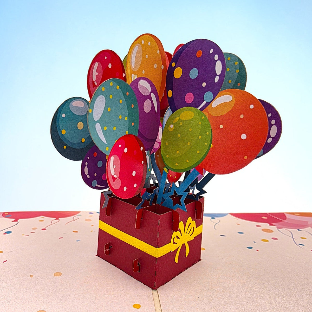 Color Pop Cards pop-up birthday card featuring a red gift box with a yellow ribbon, bursting with colorful balloons.