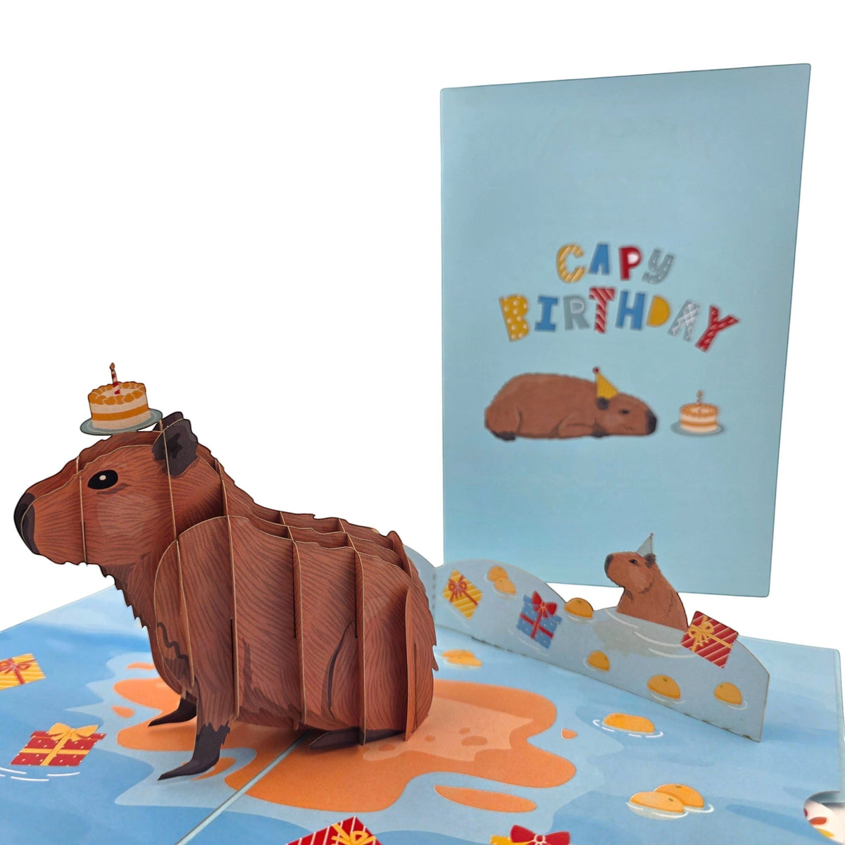 Color Pop Cards 3D pop-up birthday card featuring a brown capybara with a cake on its head, surrounded by confetti and gift boxes.