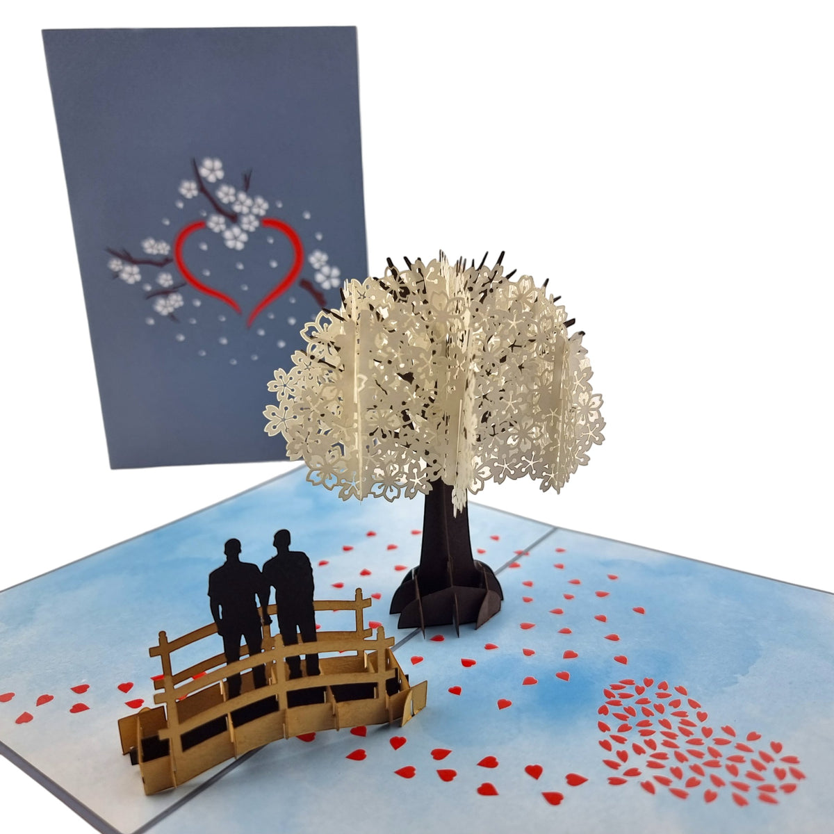 Color Pop Cards pop-up card featuring a white cherry blossom tree, a bridge with a same-sex male couple, and scattered red hearts.