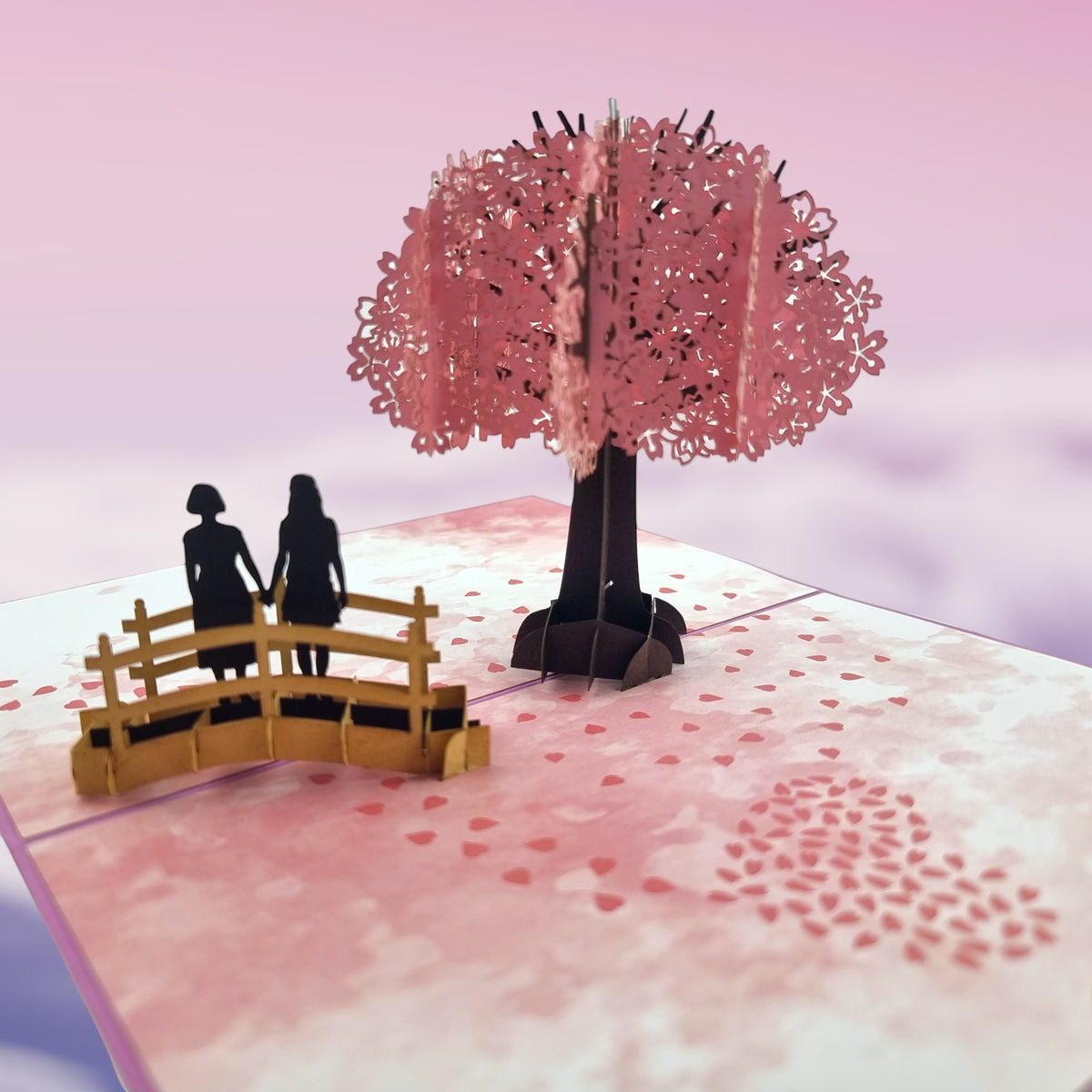 Color Pop Cards pop-up card with a cherry blossom tree and a same-sex female couple on a bridge.