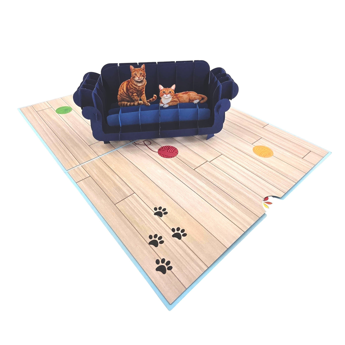 Color Pop Cards blue pop-up card with two ginger cats on a navy sofa, wood floor, paw prints, and yarn balls.