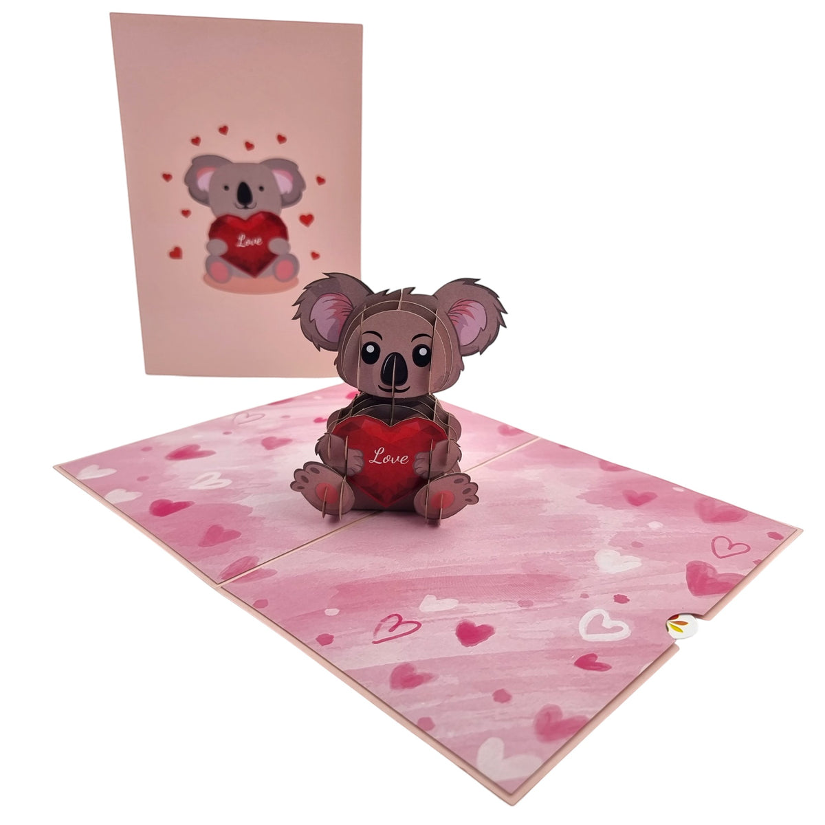 Color Pop Cards pop-up card featuring a 3D koala holding a red heart with 'Love' written on it. Pink hearts adorn the card.