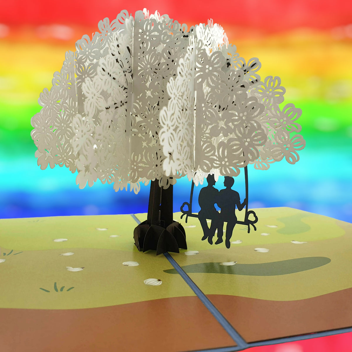 Color Pop Cards pop-up card featuring two men on a swing under a white floral tree. Rainbow background.