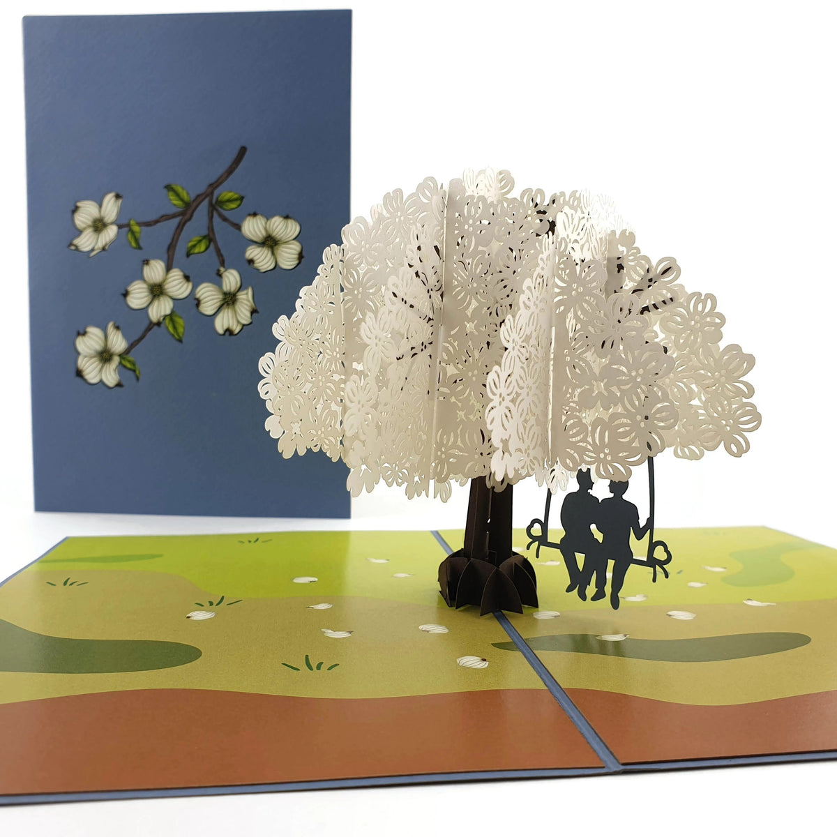 Color Pop Cards pop-up card featuring a white tree with two men on a swing, and a blue cover with floral art.