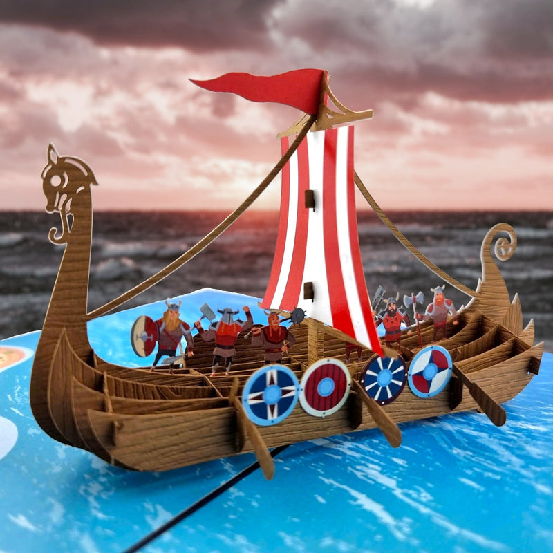 Color Pop Cards Viking ship pop-up card with red and white striped sail, shields, and Viking figures. Intricate details.