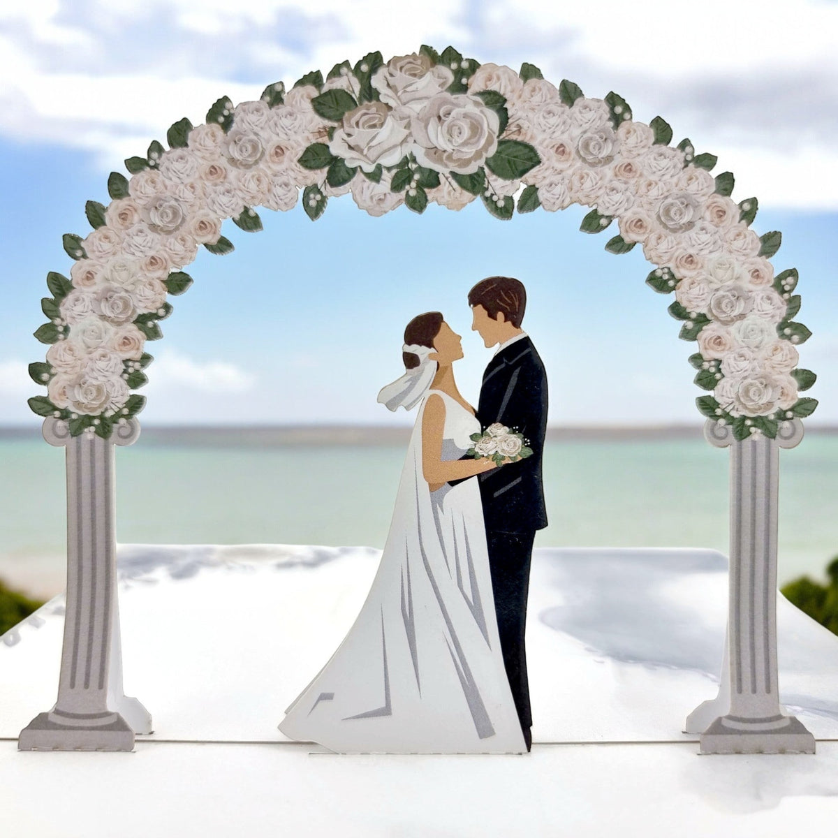 Color Pop Cards wedding day pop-up card featuring a bride and groom under a floral arch. White roses adorn the arch.