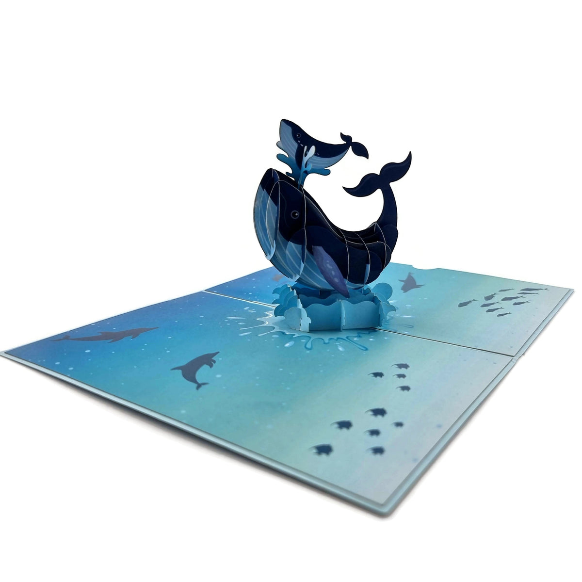 Color Pop Cards blue whale family pop up greeting card with baby whale on water spout. Card features ocean scene with dolphins and fish.