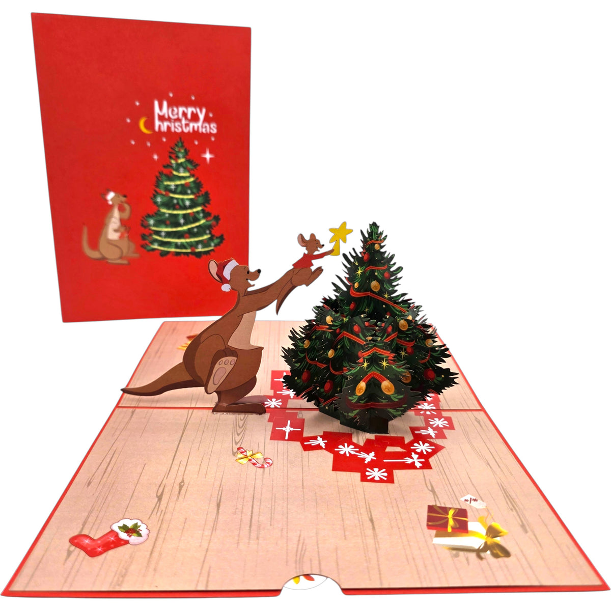 A 3D pop-up Christmas card featuring a decorated Christmas tree, a brown cartoon kangaroo wearing a Santa hat, and festive details on a light wood floor, with the red back of the card showing 'Merry Christmas' and a kangaroo under a tree.